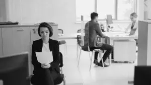 Young woman looking nervous waiting for a job interview, reading her paper resume. 
